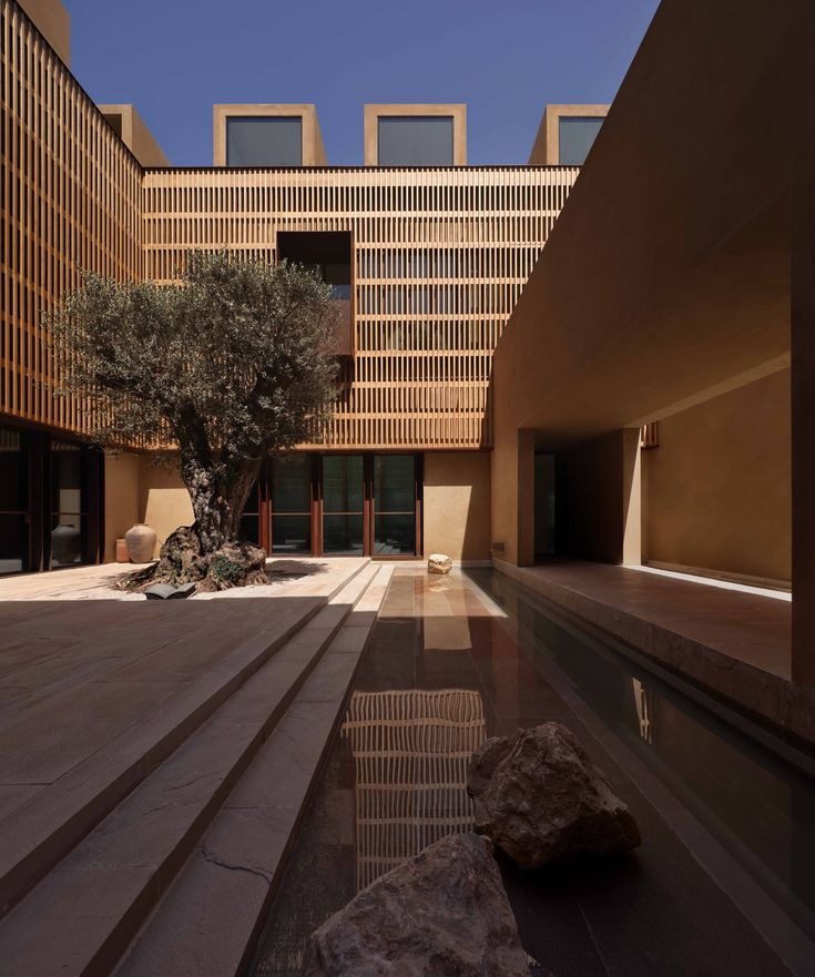 A shaded courtyard with warm stone, timber screens and a narrow reflecting pool